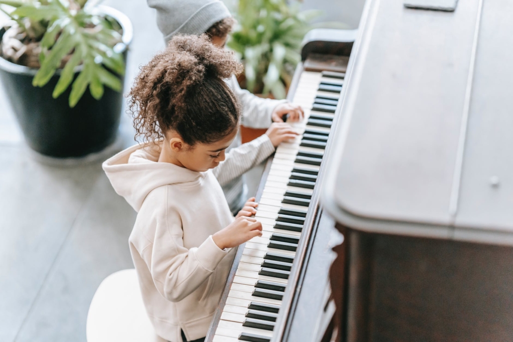 unrecognizable ethnic kids playing on piano in light room