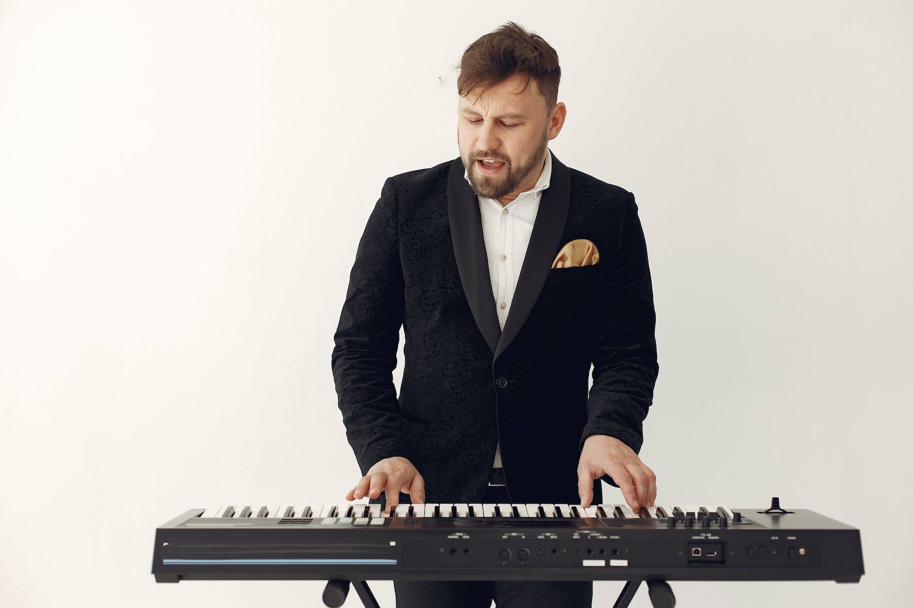 stylish adult bearded man singing and playing synthesizer